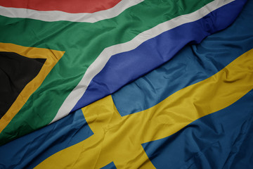 waving colorful flag of sweden and national flag of south africa.