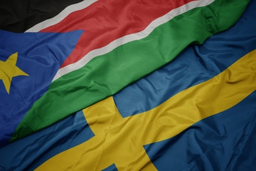 waving colorful flag of sweden and national flag of south sudan.