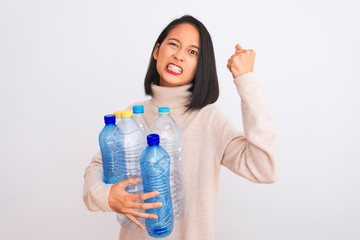 Young beautiful chinese woman recycling plastic bottles over isolated white background annoyed and frustrated shouting with anger, crazy and yelling with raised hand, anger concept