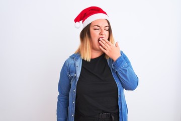 Young beautiful woman wearing Christmas Santa hat standing over isolated white background bored yawning tired covering mouth with hand. Restless and sleepiness.