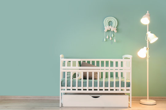 Stylish Baby Bed With Lamp Near Color Wall In Interior Of Children's Room