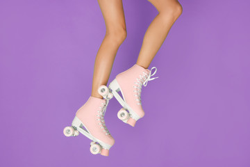 Long legs in a vintage pink roller skate isolated on violet background.