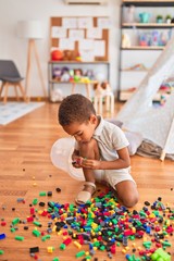 Beautiful african american toddler playing with small building blocks at kindergarten