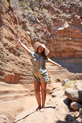 Young beauitufl hiker woman trekking natural orange mountain with arms raised celebrating summer holidays