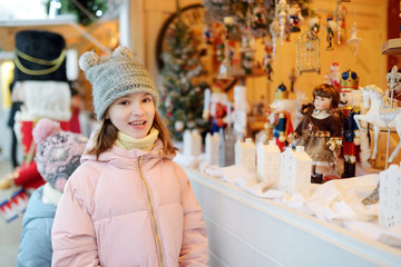 Fototapeta na wymiar Young girl looking at Christmas dolls and decorations sold at Christmas market in Vilnius, Lithuania.