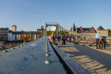 Close up view on steel handrail of balustrade on footbridge called Iron Bridge, Eiserner Steg, cross Main River in Frankfurt, Germany and blur background crowd of tourists.