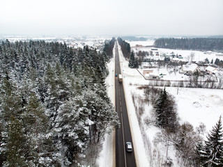 Beautiful aerial view of snow covered pine forests and a road winding among trees. Rime ice and hoar frost covering trees. Scenic winter landscape in Vilnius, Lithuania.