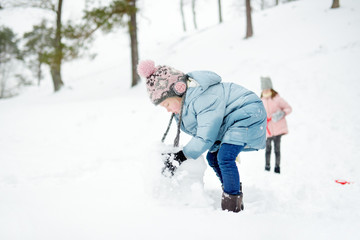 Fototapeta na wymiar Adorable young girl having fun in beautiful winter park. Cute child playing in a snow. Winter activities for family with kids.