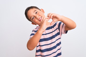 Beautiful kid boy wearing casual striped t-shirt standing over isolated white background smiling in love doing heart symbol shape with hands. Romantic concept.