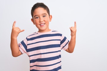 Beautiful kid boy wearing casual striped t-shirt standing over isolated white background shouting with crazy expression doing rock symbol with hands up. Music star. Heavy concept.