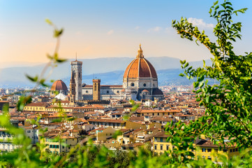 Fototapeta premium Florence, Italy: scenic view on famous italian town with Duomo at sunset with green leaves