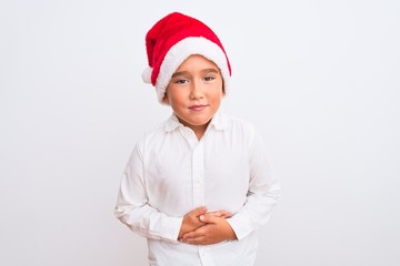 Beautiful kid boy wearing Christmas Santa hat standing over isolated white background with hand on stomach because indigestion, painful illness feeling unwell. Ache concept.