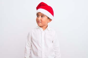 Beautiful kid boy wearing Christmas Santa hat standing over isolated white background smiling looking to the side and staring away thinking.