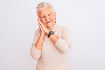 Senior grey-haired woman wearing turtleneck sweater standing over isolated white background sleeping tired dreaming and posing with hands together while smiling with closed eyes.