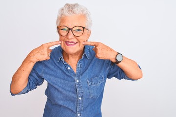 Senior grey-haired woman wearing denim shirt and glasses over isolated white background smiling...