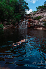 Mujer relajada en lago, al pie de una cascada