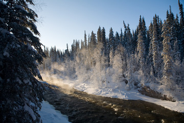 Steam rises above river rapids on a cold and snowy winter day