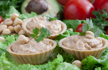 Canapes with hummus on a vegetable background