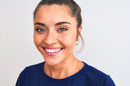 Young beautiful woman wearing blue casual t-shirt standing over isolated white background with a happy face standing and smiling with a confident smile showing teeth