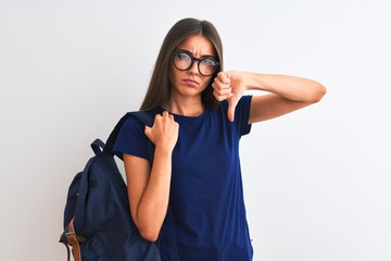 Young beautiful student woman wearing backpack and glasses over isolated white background with angry face, negative sign showing dislike with thumbs down, rejection concept