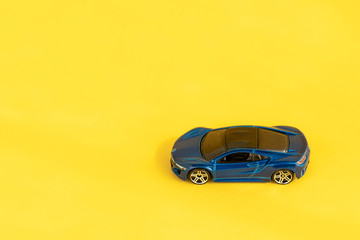 Fototapeta na wymiar ids toy car on colorful yellow background. Modern design. Minimal creative flatlay composition. Automobile repair and transportation service. Toy car delivery. Travel background. Copy space, top view.