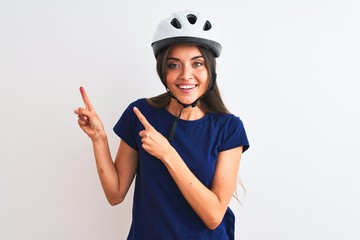 Young beautiful cyclist woman wearing security bike helmet over isolated white background smiling and looking at the camera pointing with two hands and fingers to the side.