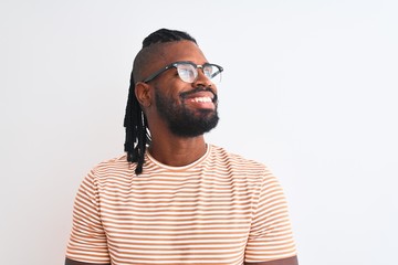 African american man wearing striped t-shirt and glasses over isolated white background looking away to side with smile on face, natural expression. Laughing confident.