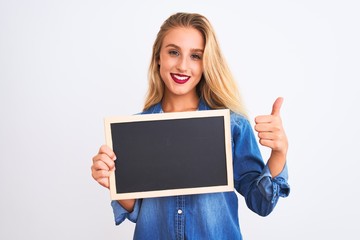 Young beautiful teacher woman holding blackboard standing over isolated white background happy with big smile doing ok sign, thumb up with fingers, excellent sign