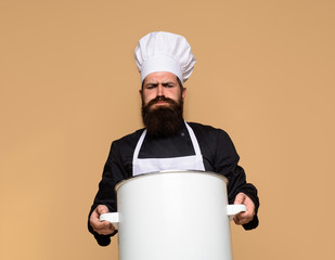 Chef in uniform cooking with cooking pot. Chef, cook or baker with saucepan in hand. Professional chef in uniform and hat holds pot. Cooking, food, profession concept. Casserole. Male chef holds pan.