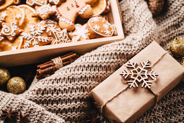 Christmas and New Year traditions concept. Gingerbread cookies, decorations, gift boxes and knitted blanket
