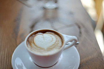 cup of coffee with cream on wooden background