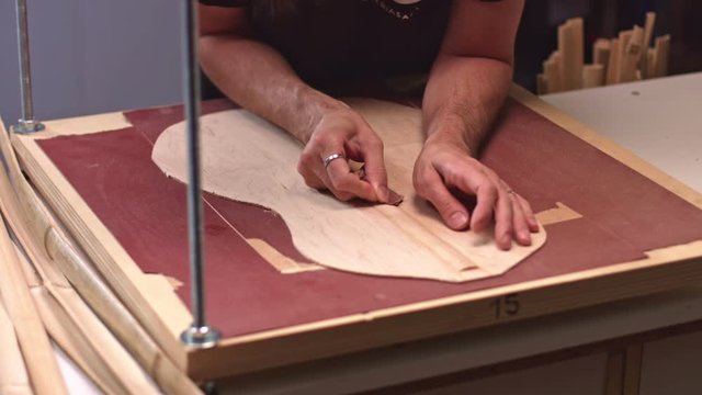 Luthier glues central brace for acoustic guitar