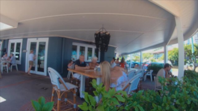 People Dining Alfresco & Relaxing. Al Fresco Dining At Cafe Restaurant.Groups Of Male & Female Friends Talking Together At Table. Woman & Man Couple & Young Girl Sitting On Chairs In Outside Eatery