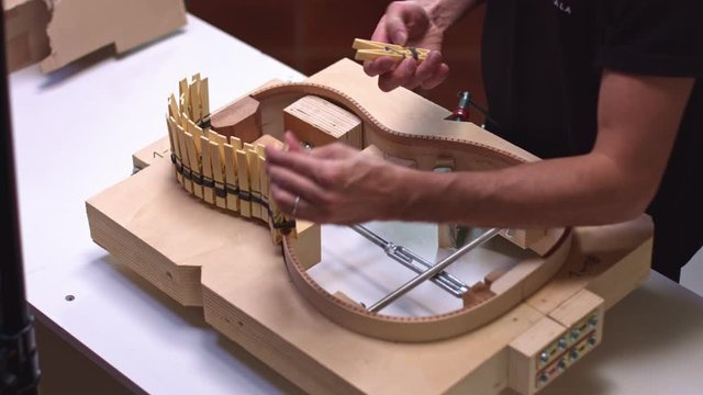 Guitar maker removes clothespins from acoustic guitar structure