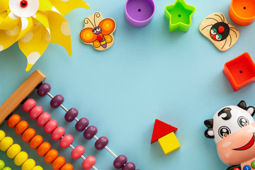 Top view on children's educational games, frame from kids toys on blue paper background. Сubes, stars, circles, cow, pinwheel, abacus, cute butterfly, spider. Flat lay, copy space