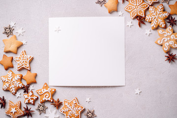 Christmas composition, New Year greeting card. White mockup paper sheet with festive food decorations and gingerbread cookies on white background. Copy space.
