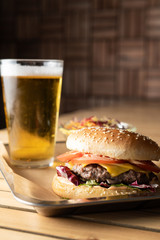 Cheeseburger with beef patty in the foreground with beer on the background