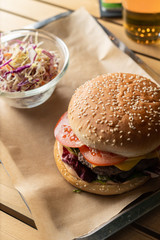 Classic juicy burger with cheddar cheese and coleslaw on tray with craft paper
