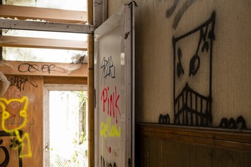 Horizontal shot of a door with colorful drawings and a scary drawing on the wall during daytime