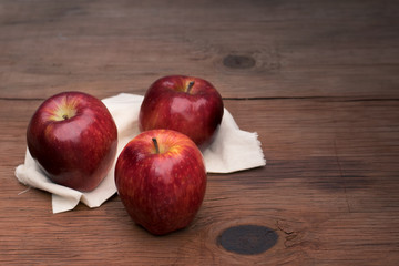 three apples on a cloth on a rustic table