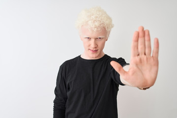 Young albino blond man wearing black t-shirt standing over isolated white background doing stop sing with palm of the hand. Warning expression with negative and serious gesture on the face.