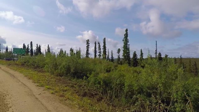 Pov shot, driving a dirt road, in Alaskan wilderness, passing Eagle, Yukon river and Fort Egbert sign, on a sunny day, in Alaska, USA