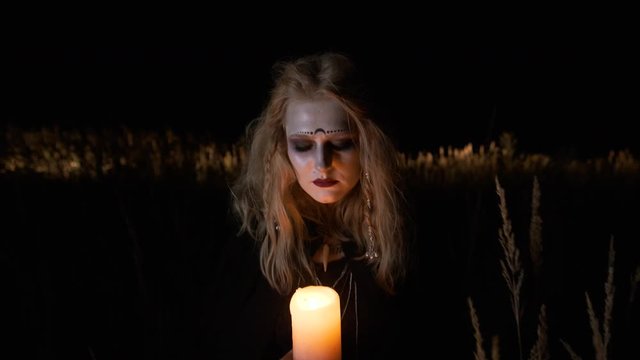 Halloween Image. Young Witch Goes At Night With Candle In Her Hands.