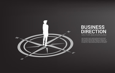 Silhouette of businessman standing at center of compass on floor.Concept of career path and business direction