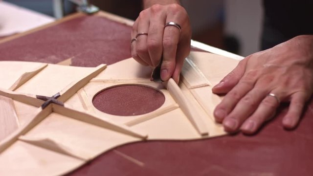 Luthier sanding braces of guitar soundboard