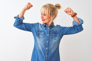 Middle age woman wearing casual denim shirt standing over isolated white background showing arms...