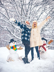 Students party and Christmas celebration. Happy girl playing with a snowman on a snowy winter walk....