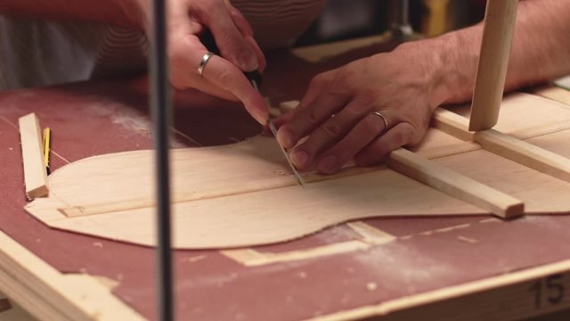 Luthier cuts braces to insert horizontal braces in acoustic guitar soundboard