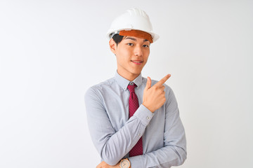 Chinese architect man wearing tie and helmet standing over isolated white background cheerful with a smile of face pointing with hand and finger up to the side with happy and natural expression