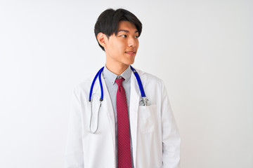 Chinese doctor man wearing coat tie and stethoscope over isolated white background looking away to side with smile on face, natural expression. Laughing confident.